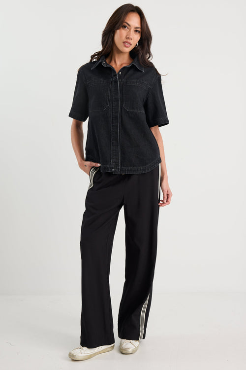 Woman wearing a black denim shirt and pants on a white background