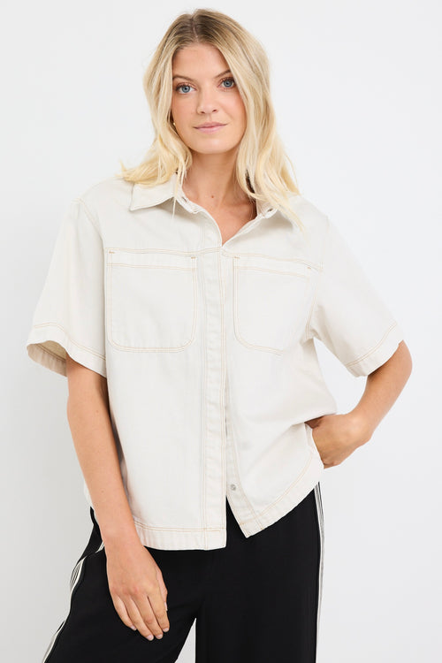 model wears an ecru denim short sleeve shirt with black pants
col_pattern