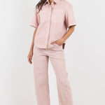 Woman wearing a pink outfit with a shirt and pants on a white background