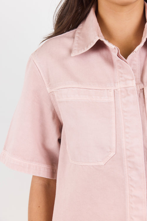 Close-up of a person wearing a light pink shirt with a collar on a white background