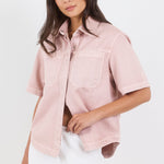 Woman wearing a light pink shirt with short sleeves on a white background