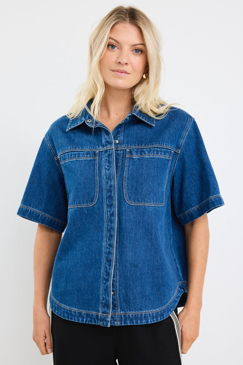 model wears a blue short sleeve denim shirt with black pants