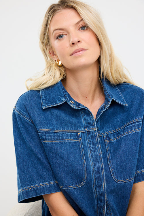 model wears a blue short sleeve denim shirt with black pants