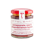 A glass jar of Ottolenghi pomegranate, rose & preserved lemon harissa paste with a red lid and white label, centered on a plain white background.