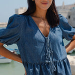 Woman wearing a blue denim top with a blurred background