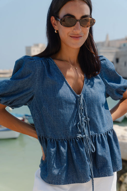 Woman wearing a blue denim top with a blurred background