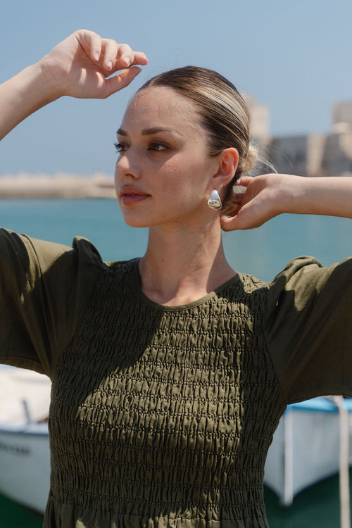 Woman adjusting her hair with a scenic background of water and boats.