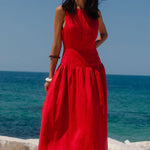 Woman in a red dress standing by the ocean on a clear day