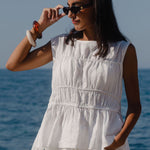 Woman in a white outfit standing by the ocean