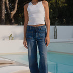Woman standing by a pool with trees in the background