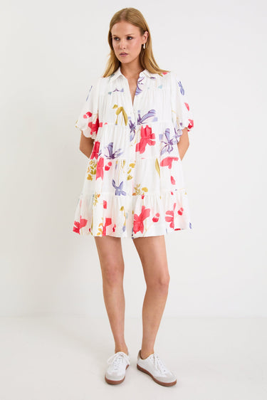 Model wearing a cream mini tiered shirt dress with colourful poppy floral print, puff sleeves and a button front.