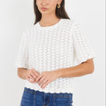 Woman wearing a white lace top and blue jeans on a white background