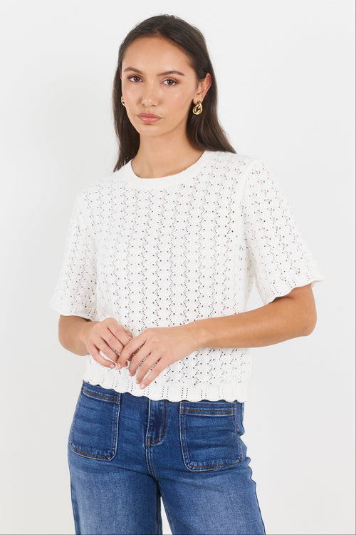 Woman wearing a white lace top and blue jeans on a white background