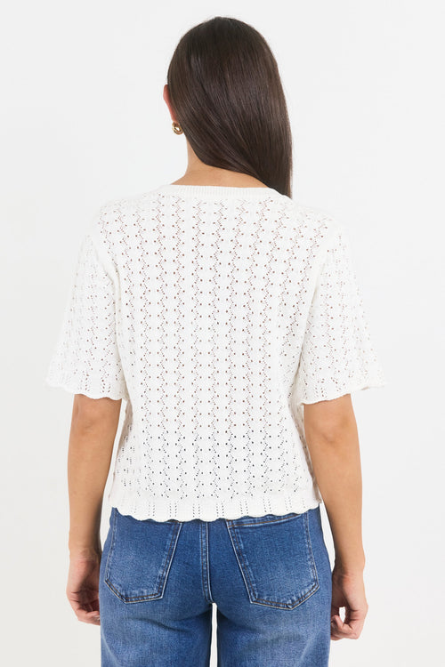 Woman wearing a white lace top and blue jeans on a white background