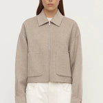 Woman wearing a beige jacket with a plain background