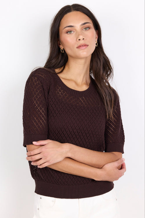 Woman wearing a brown knit sweater against a white background