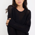 Woman wearing a black knit sweater against a white background