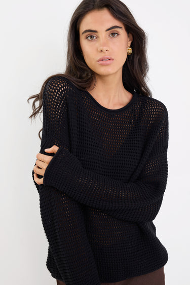 Woman wearing a black knit sweater against a white background