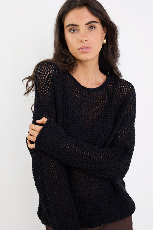 Woman wearing a black knit sweater against a white background