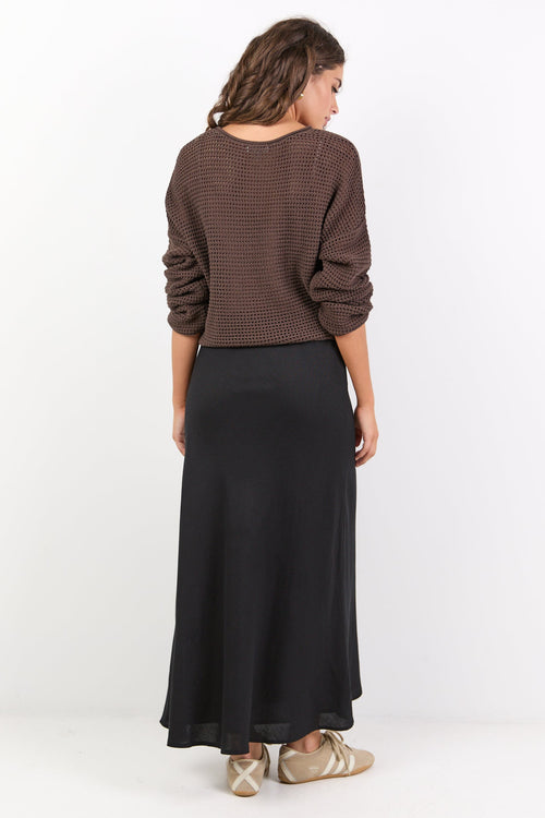Woman wearing a brown sweater and black skirt on a white background