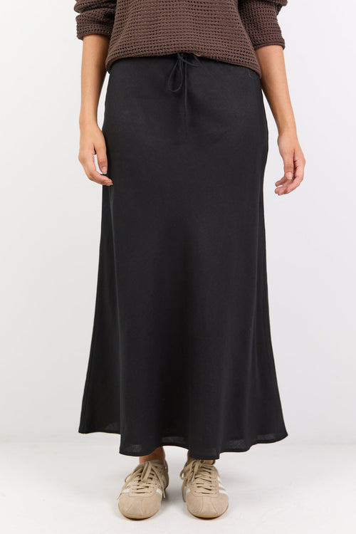 Person wearing a brown sweater and black skirt on a white background