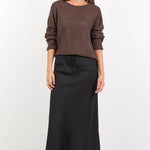 Woman wearing a brown sweater and black skirt on a white background