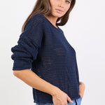 Woman wearing a navy blue knitted sweater and blue jeans on a white background