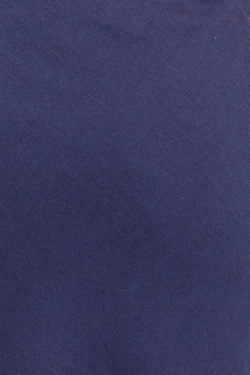 Navy blue skirt worn with a white textured top on a plain background