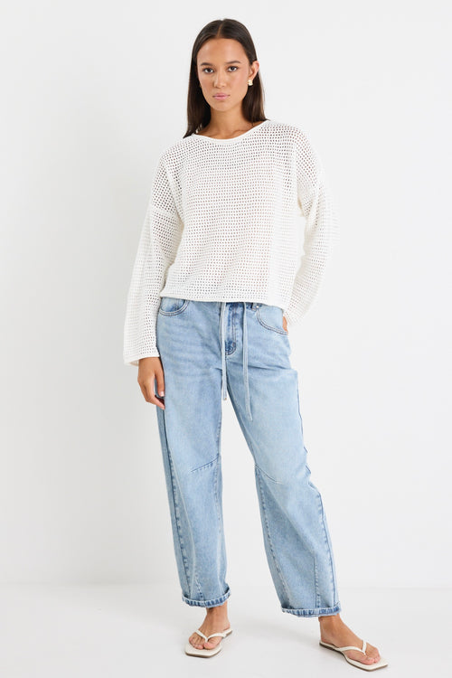 model wears white knit jumper and light blue jeans
