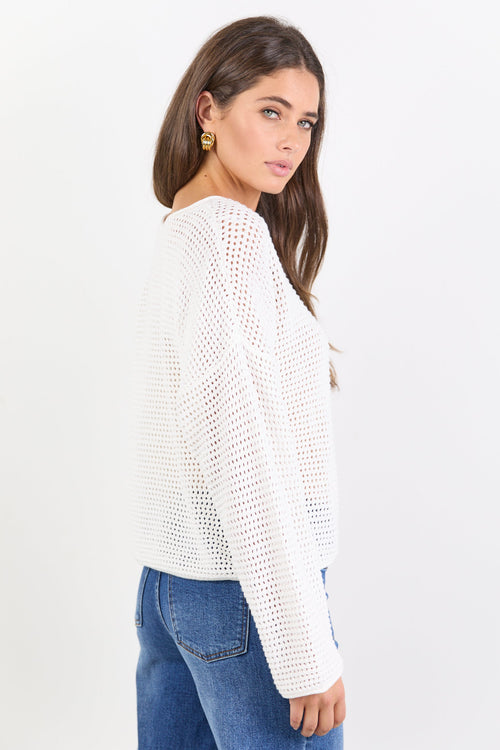 Woman wearing a white knitted sweater and blue jeans on a white background