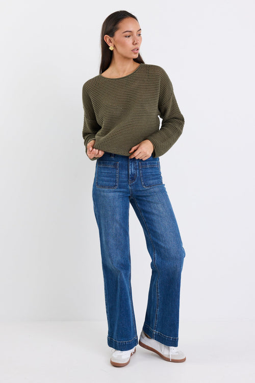 woman wearing a khaki knit and blue jeans