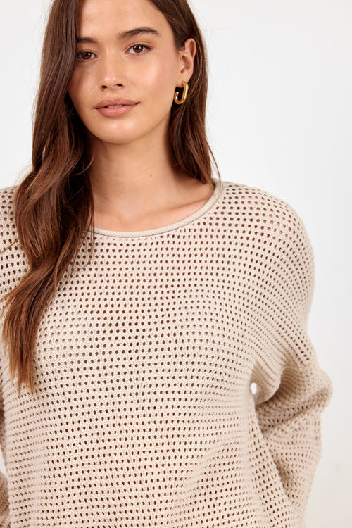 A woman wearing a beige open-knit crewneck sweater, shown from the chest up against a plain white background.
col_pattern