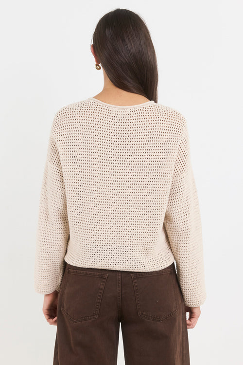 Person wearing a beige knitted sweater and brown pants on a white background