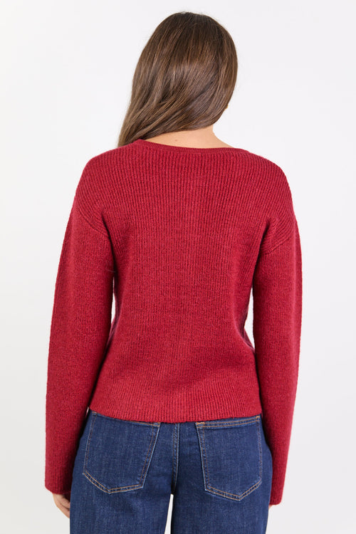 Person wearing a red sweater and blue jeans on a white background
