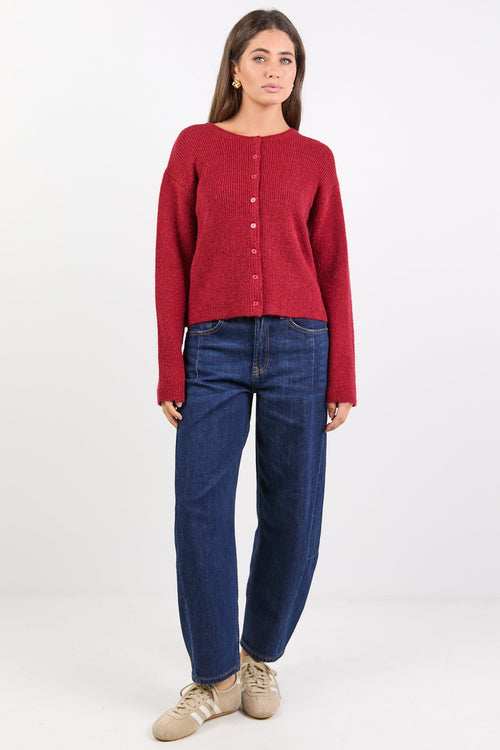 Person wearing a red cardigan and blue jeans on a white background