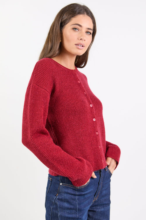 Woman wearing a red sweater and blue jeans on a white background