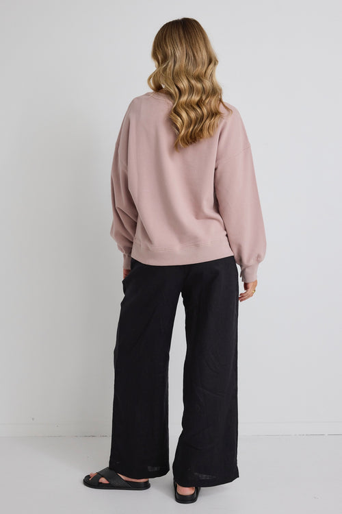 model wears pink jumper and black pants