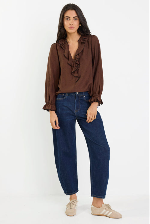Woman wearing a brown blouse and blue jeans on a white background