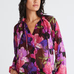 Model wears a purple floral blouse