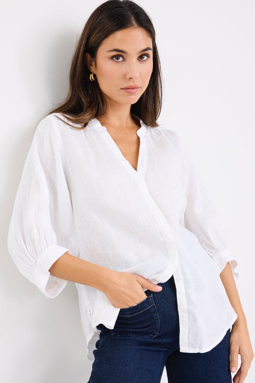 model wears a white linen blouse with dark denim jeans
