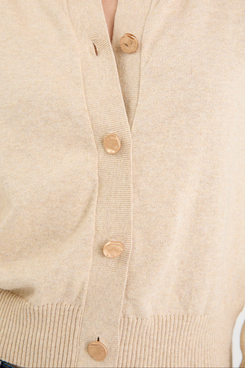 Close-up of a beige cardigan with buttons on a light background
