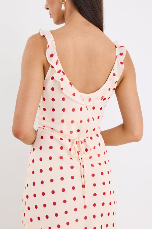 Woman wearing a cream and red polka dot slip maxi dress with adjustable straps, V-neckline, and a flowing bias-cut design.