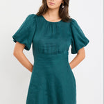 Woman wearing a forest green mini dress with puff sleeves, bias-cut shape, and fitted waist, styled simply for an elegant look.
