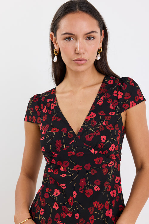 Woman wearing a black dress with red floral pattern on a white background