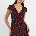 Woman wearing a black dress with red floral pattern on a white background