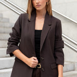 Woman wearing a brown blazer and pants standing on a staircase.