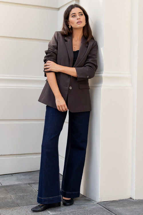 Women in chocolate blazer and denim jeans.