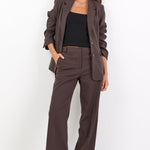 Woman wearing a brown suit standing against a white background