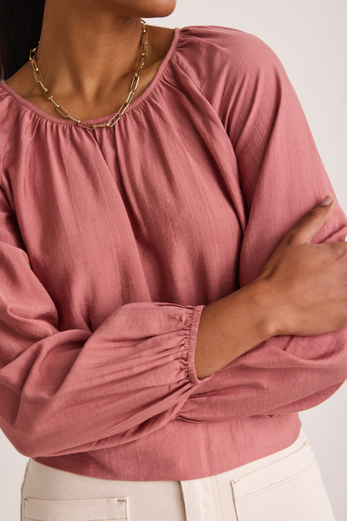 model wears a pink blouse 