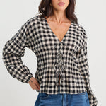 Woman wearing a black and white checkered blouse with blue jeans on a white background